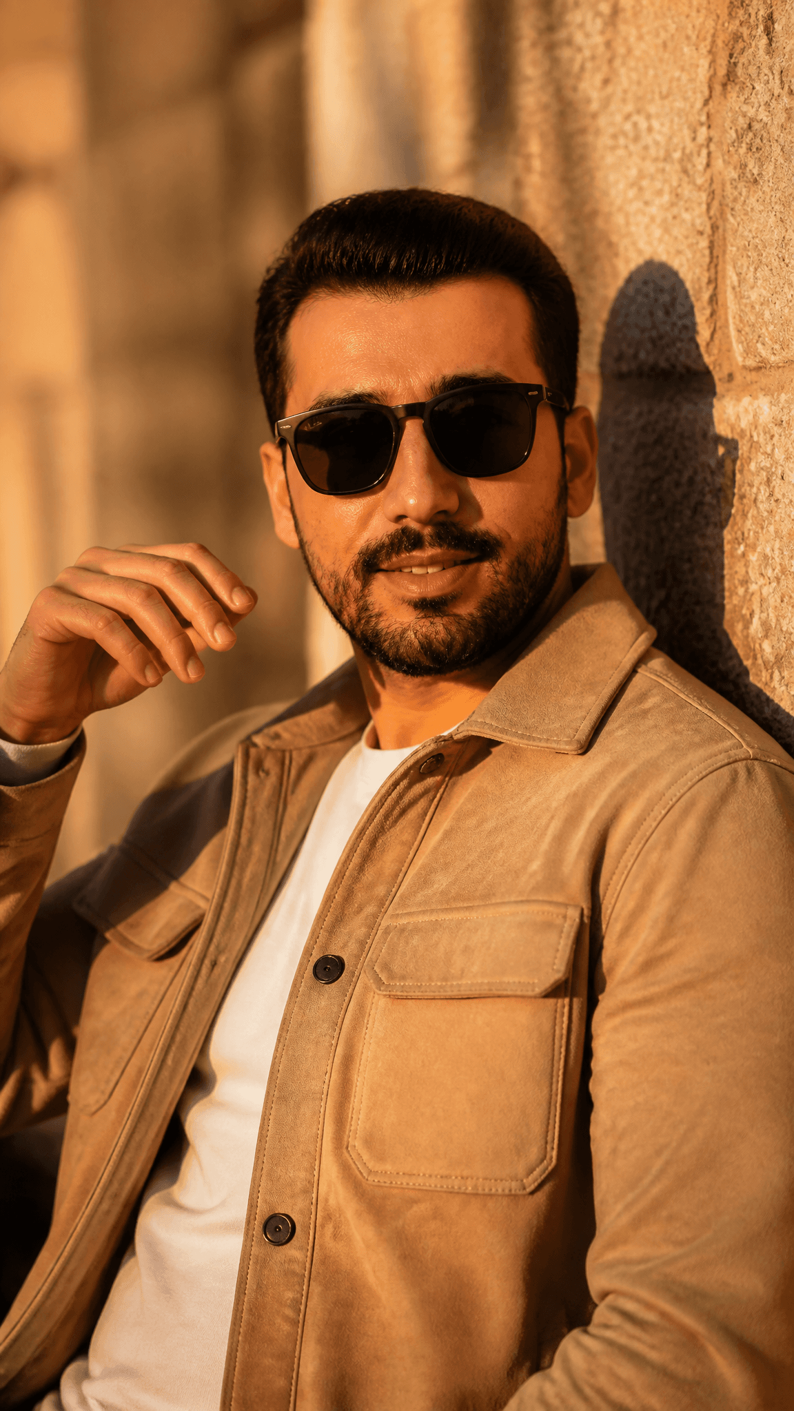 A cinematic golden hour portrait of a stylish man leaning ag