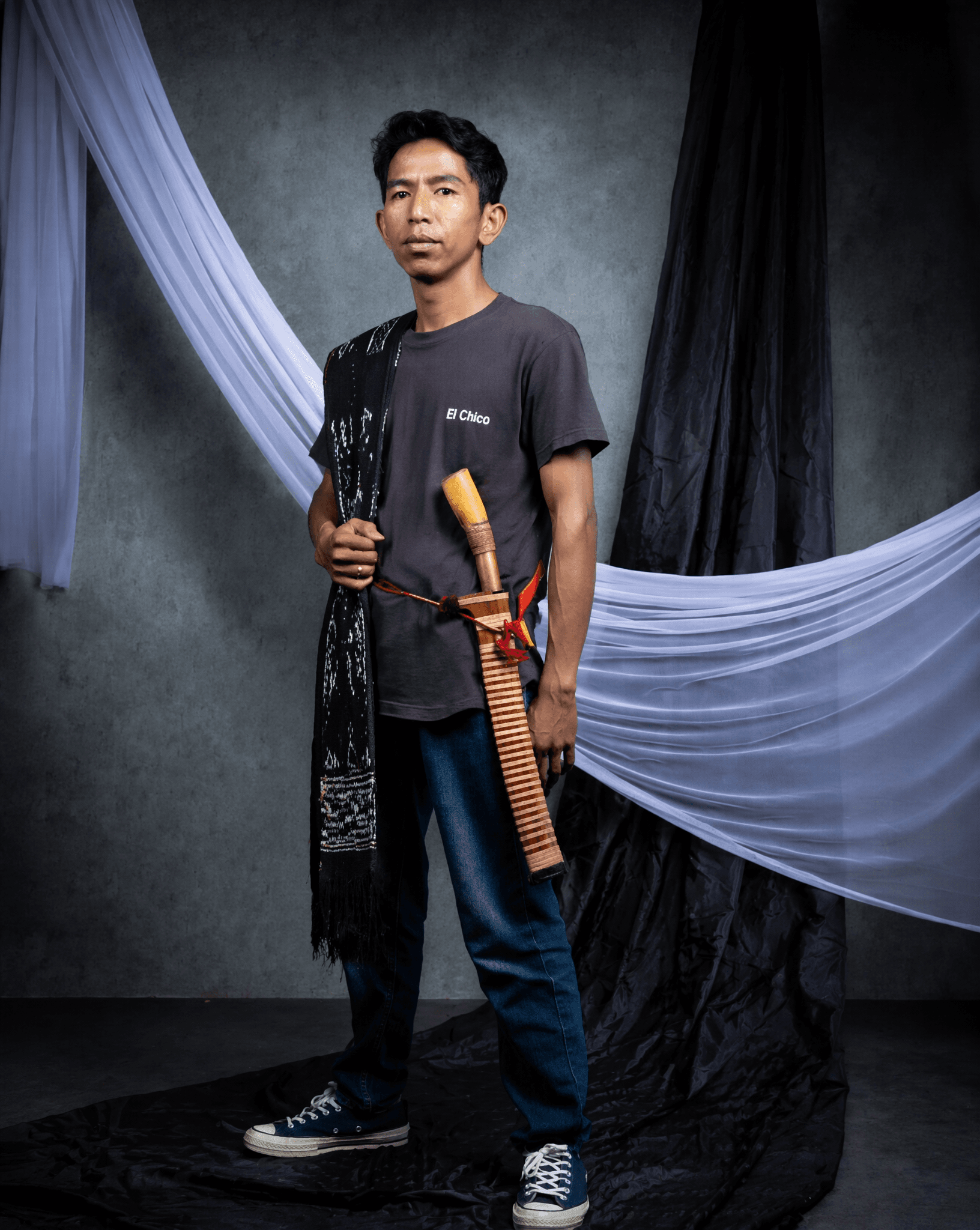 A Southeast Asian man stands centered in a studio portrait,