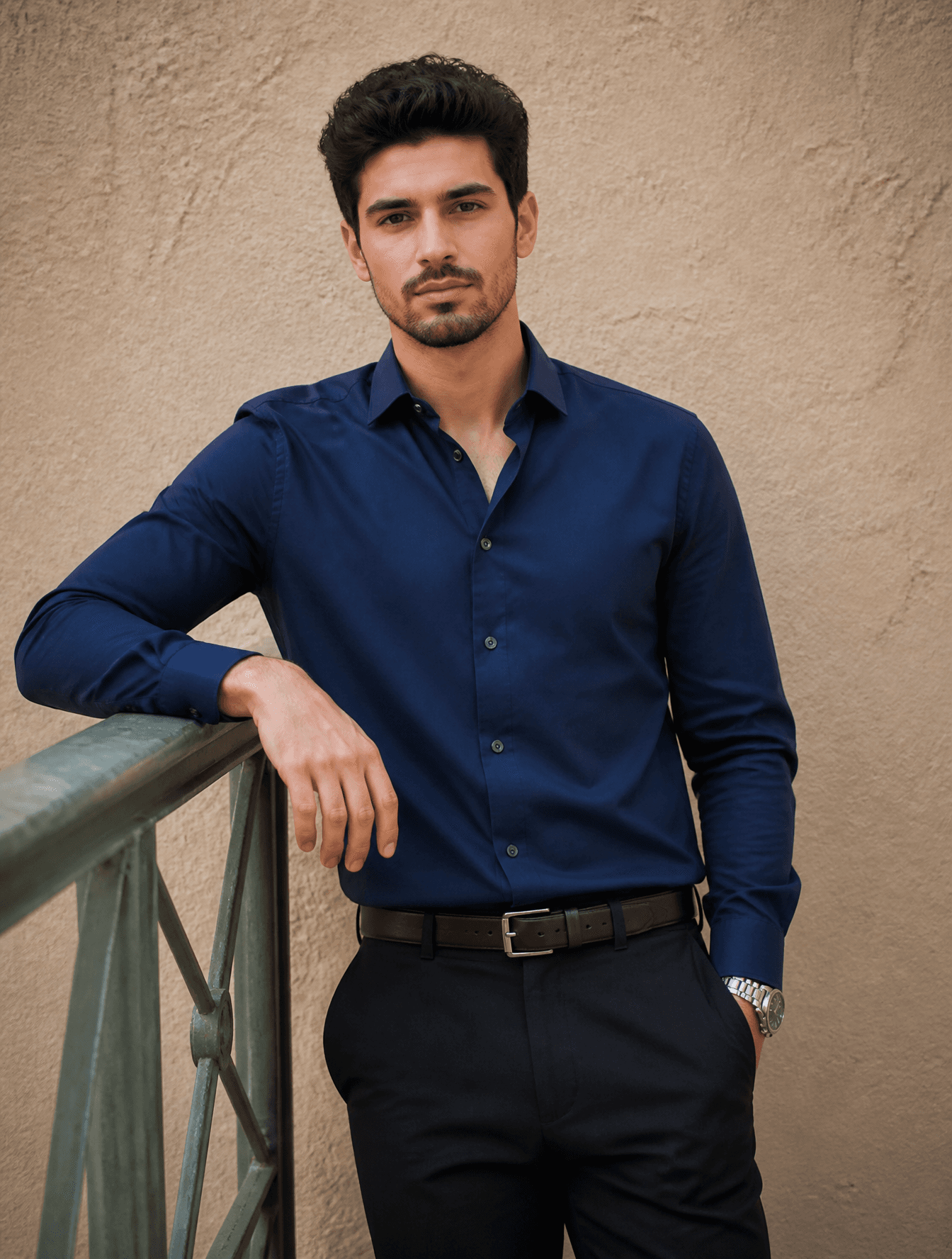 A young man with dark, styled hair and light stubble stands 