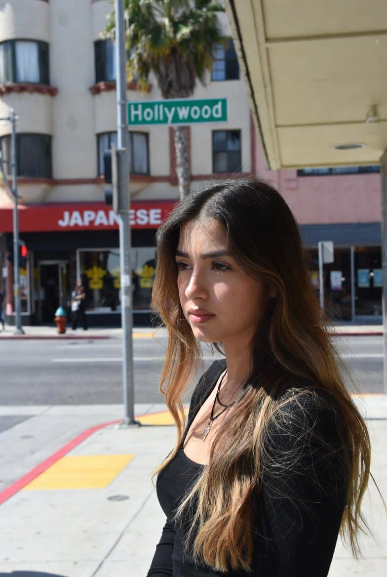A strikingly beautiful young woman in her early 20s standing