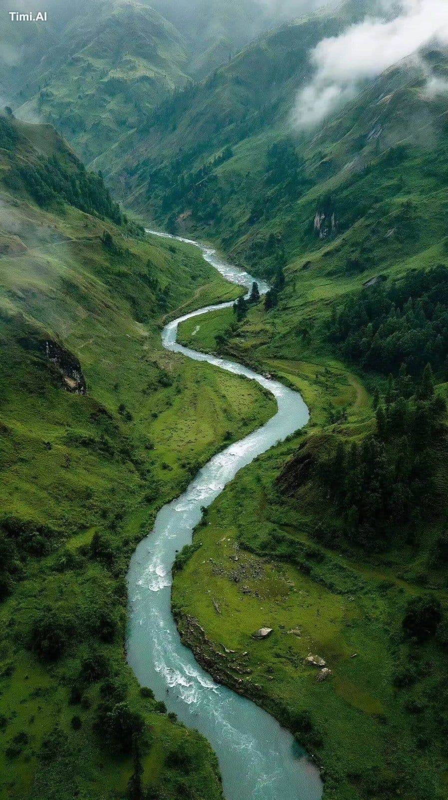 Wide aerial shot of a meandering mountain river cutting thro