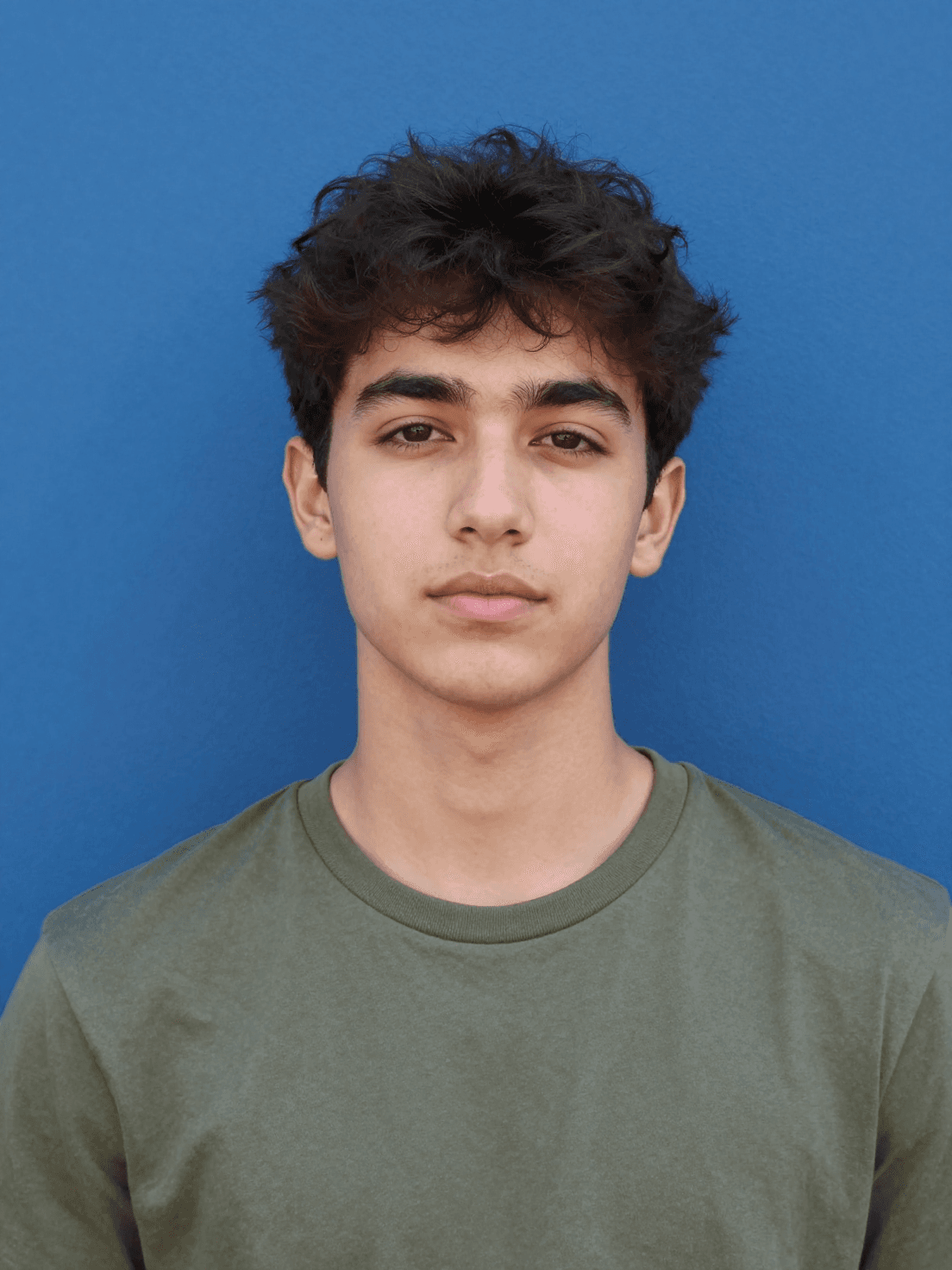 A young man with dark, textured hair poses for a centered po