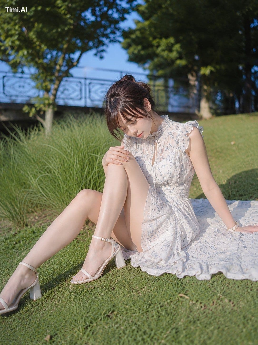 縦位置の写真。緑豊かな公園の芝生に、ひとりの女性が画面中央やや右寄りに座っている。人物は全身が入る大きさで、画面の約7割